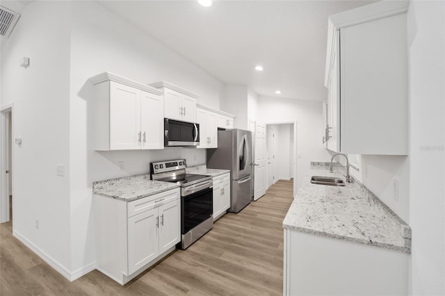 kitchen with light stone countertops, sink, stainless steel appliances, and white cabinetry