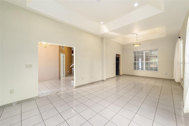 tiled empty room with a notable chandelier and a tray ceiling