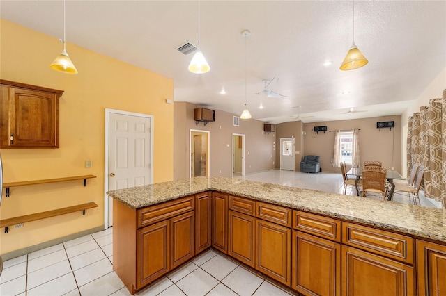 kitchen with light stone countertops, hanging light fixtures, light tile patterned floors, and kitchen peninsula