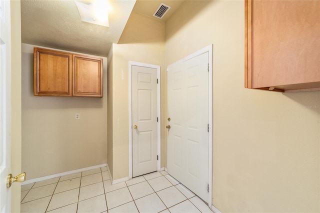 laundry room with a textured ceiling and light tile patterned floors