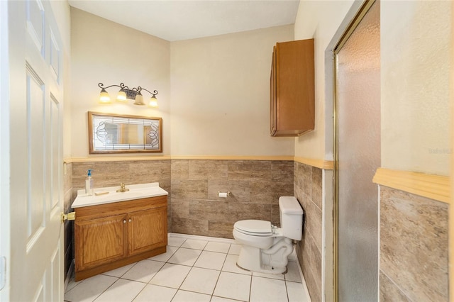 bathroom with toilet, tile walls, walk in shower, vanity, and tile patterned flooring