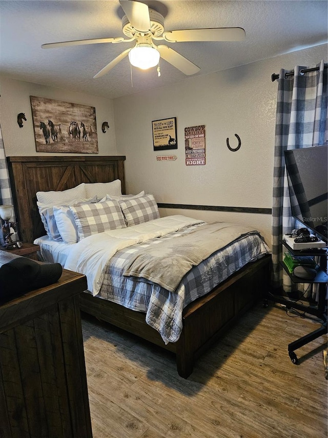 bedroom featuring wood-type flooring, ceiling fan, and a textured ceiling