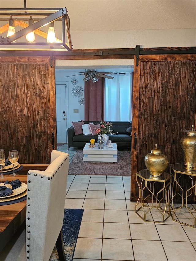 living room featuring a barn door, wood walls, and tile patterned floors