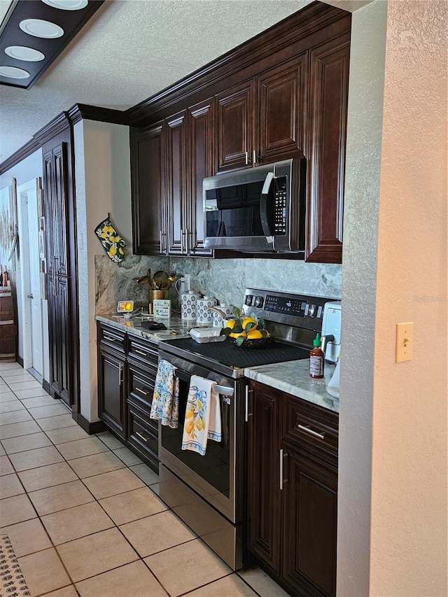 kitchen featuring light tile patterned flooring, crown molding, stainless steel appliances, backsplash, and dark brown cabinetry