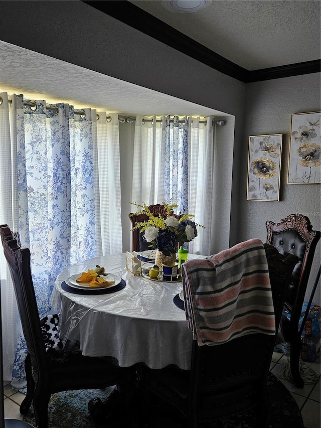 dining space featuring a textured ceiling, light tile patterned floors, and ornamental molding