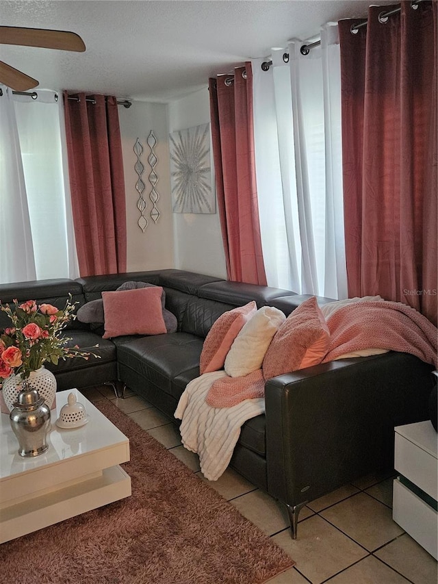 living room with a textured ceiling, light tile patterned floors, and ceiling fan