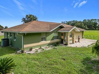 rear view of house featuring a patio, a yard, and cooling unit