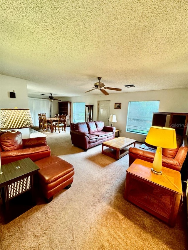 living room featuring carpet flooring, a textured ceiling, and ceiling fan