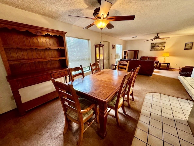 carpeted dining room with ceiling fan and a textured ceiling