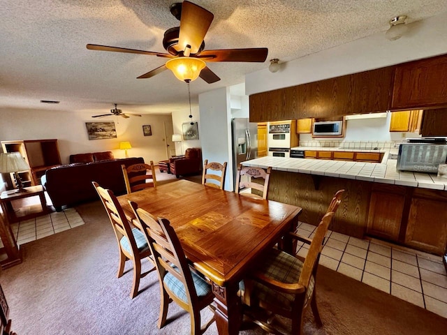 tiled dining room with ceiling fan and a textured ceiling