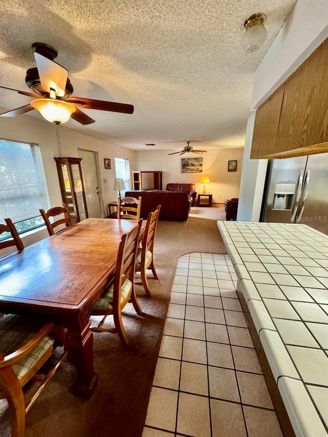 dining room with ceiling fan, tile patterned flooring, and a textured ceiling