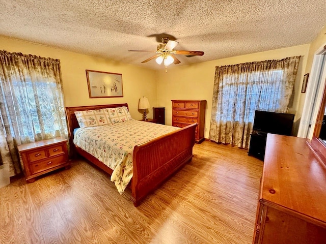 bedroom featuring ceiling fan, multiple windows, and light hardwood / wood-style floors