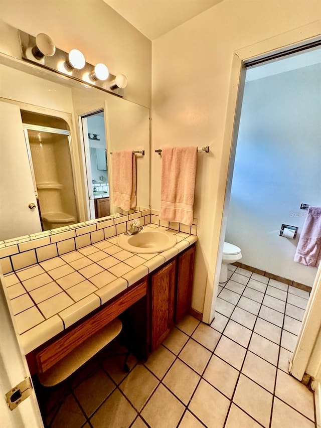 bathroom with toilet, vanity, tile patterned floors, and walk in shower