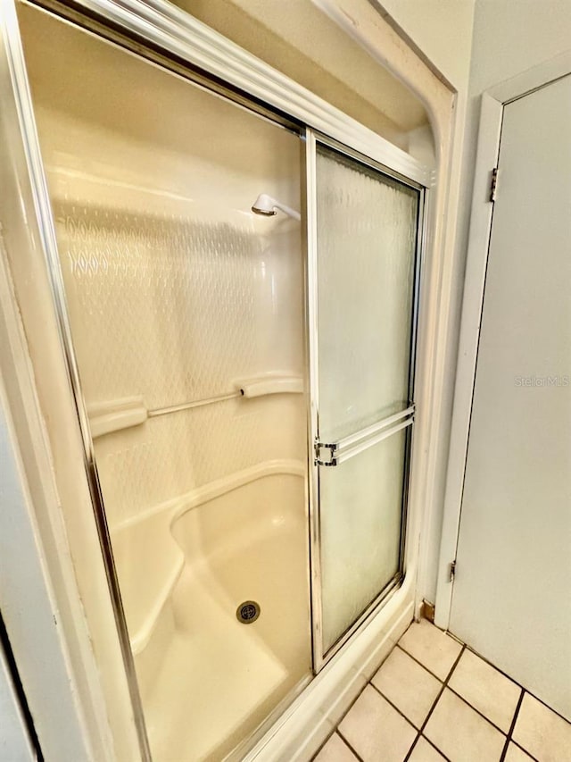 bathroom with a shower with shower door and tile patterned flooring