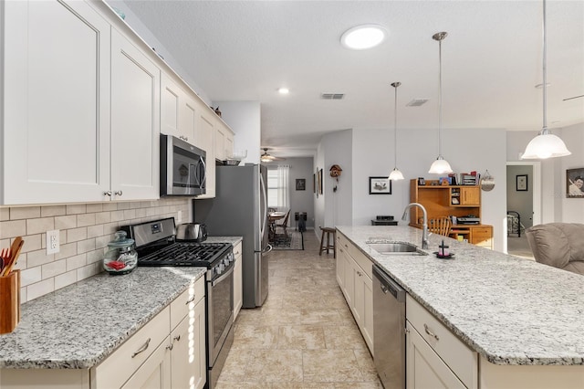 kitchen with a kitchen island with sink, pendant lighting, stainless steel appliances, and sink