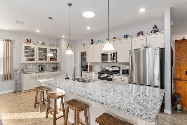 kitchen with sink, stainless steel appliances, an island with sink, decorative light fixtures, and white cabinets