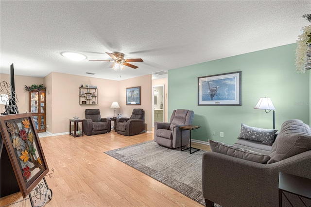 living room with ceiling fan, a textured ceiling, and wood-type flooring