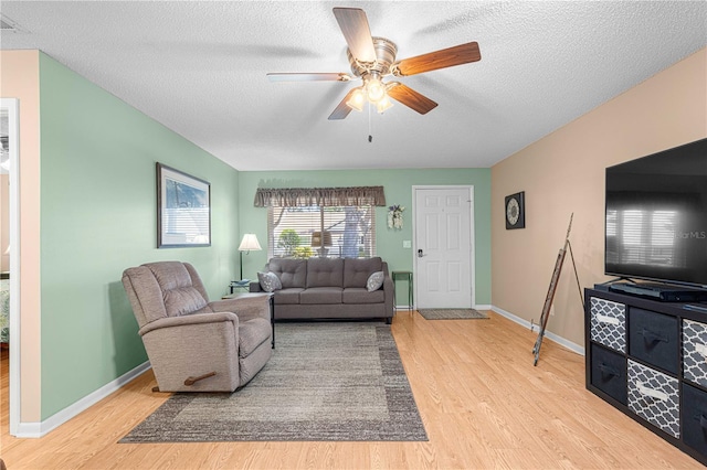 living room with ceiling fan, a textured ceiling, and light hardwood / wood-style flooring