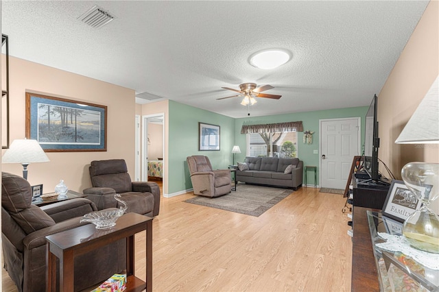 living room featuring a textured ceiling, light hardwood / wood-style floors, and ceiling fan