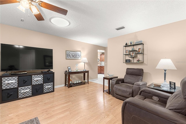 living room featuring light hardwood / wood-style floors, a textured ceiling, and ceiling fan