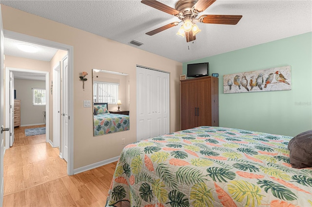 bedroom featuring light hardwood / wood-style floors, a textured ceiling, a closet, and ceiling fan