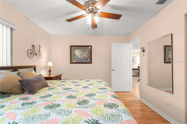 bedroom featuring ceiling fan, a textured ceiling, and light hardwood / wood-style flooring