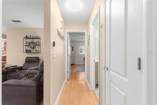 hall with light hardwood / wood-style flooring and a textured ceiling