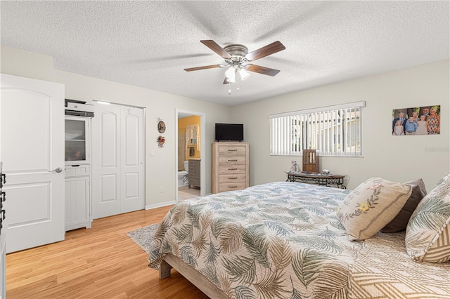 bedroom with ceiling fan, a textured ceiling, light hardwood / wood-style floors, a closet, and ensuite bath