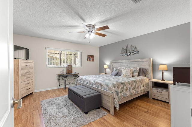 bedroom with a textured ceiling, wood-type flooring, and ceiling fan