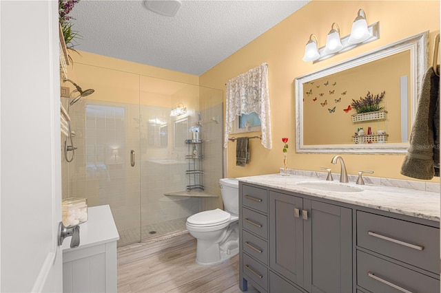 bathroom featuring vanity, toilet, hardwood / wood-style flooring, and a shower with shower door