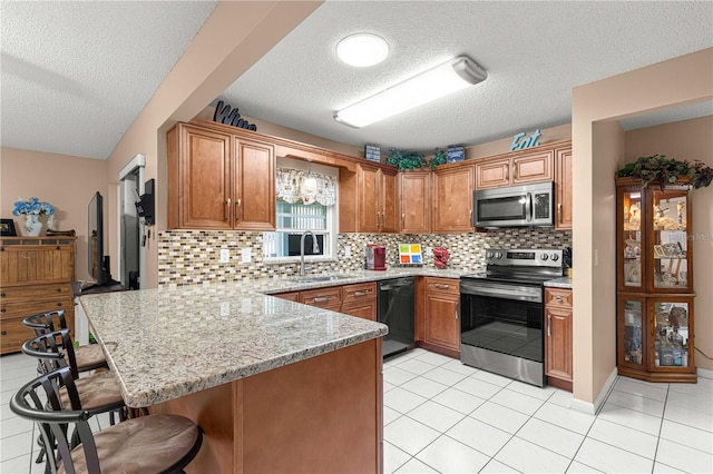 kitchen featuring decorative backsplash, a kitchen breakfast bar, kitchen peninsula, sink, and appliances with stainless steel finishes