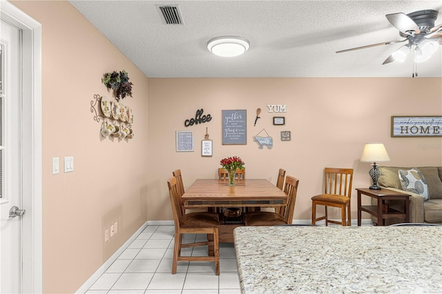 tiled dining room with a textured ceiling and ceiling fan