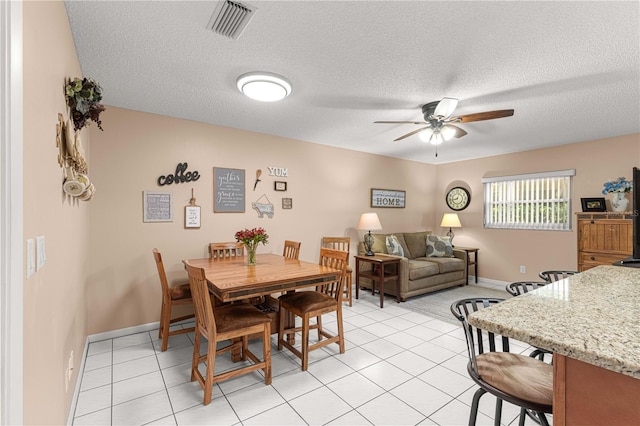 dining area featuring a textured ceiling, light tile patterned floors, and ceiling fan