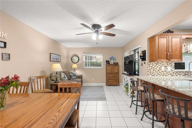 kitchen with a textured ceiling, light stone countertops, light tile patterned floors, and decorative backsplash