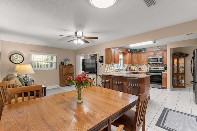 dining space featuring light tile patterned flooring, a textured ceiling, sink, and ceiling fan