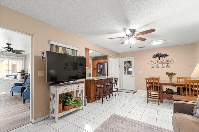 tiled living room with ceiling fan and a textured ceiling