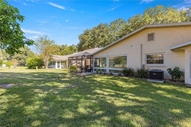 back of property with central AC, a lanai, and a lawn