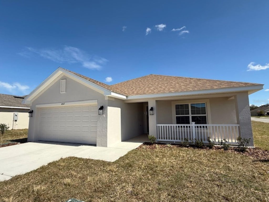 ranch-style home with stucco siding, covered porch, a front yard, a garage, and driveway