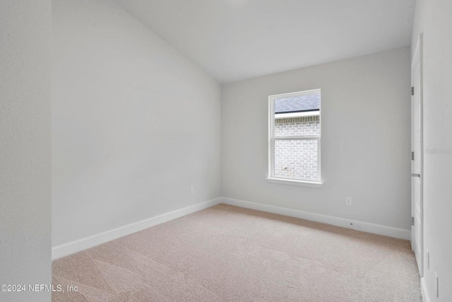 carpeted spare room with vaulted ceiling