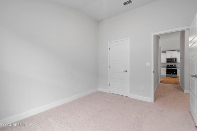 unfurnished bedroom featuring light carpet and vaulted ceiling