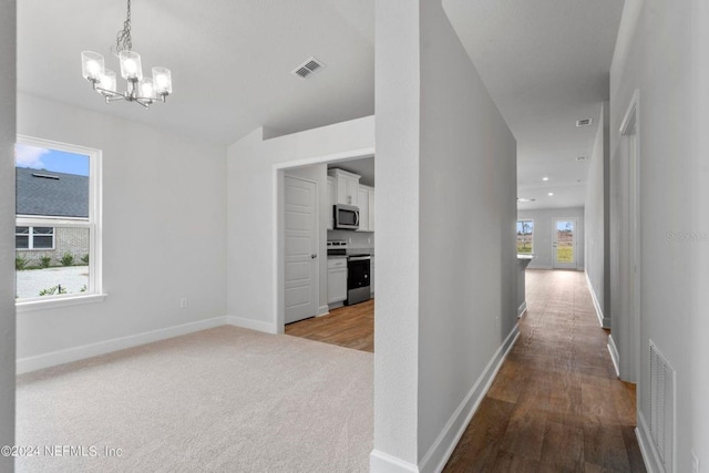 hall featuring light colored carpet and a notable chandelier