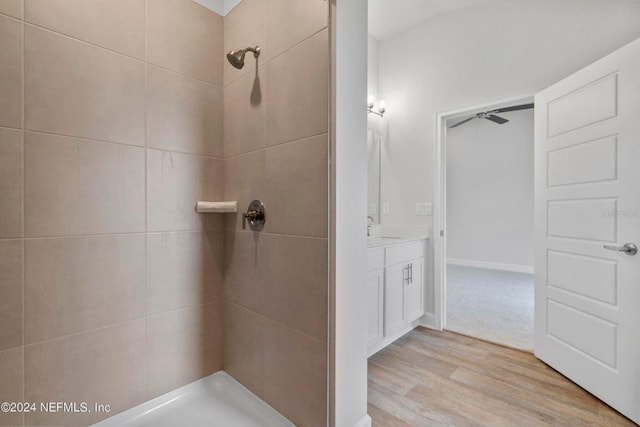 full bath featuring tiled shower, vanity, and wood finished floors