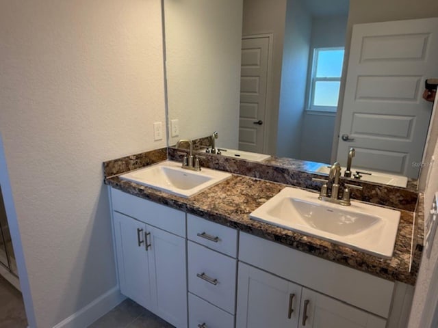 bathroom featuring double vanity, baseboards, and a sink