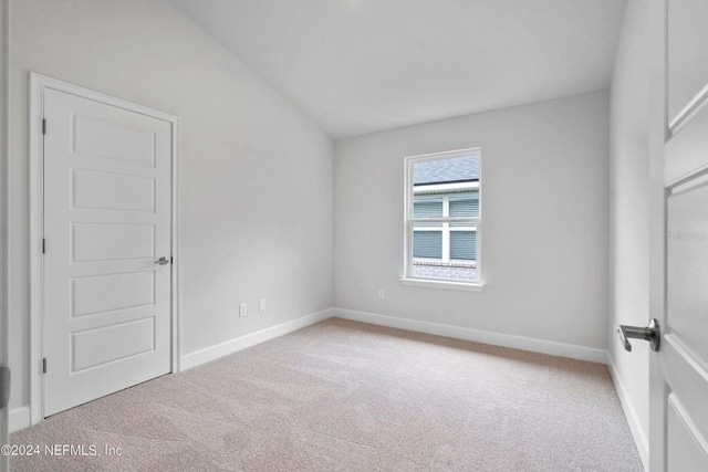 carpeted empty room with lofted ceiling and baseboards