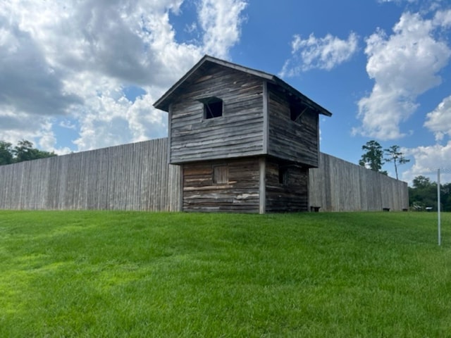 view of barn with a lawn and fence