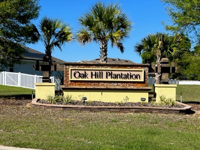 community / neighborhood sign featuring fence and a lawn