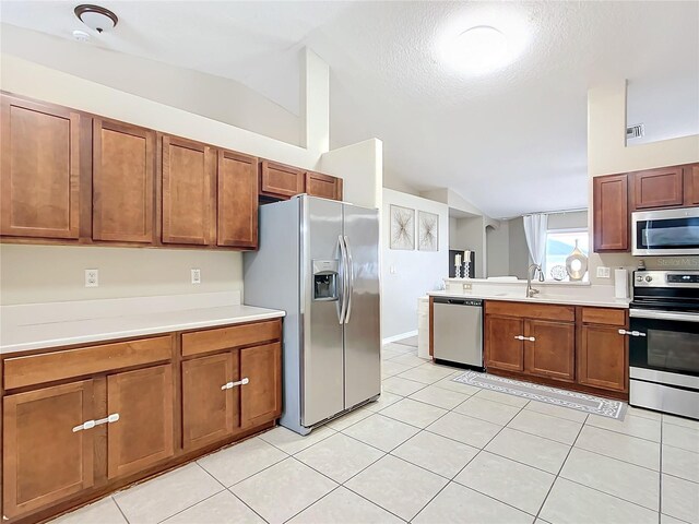 kitchen with light tile patterned flooring, appliances with stainless steel finishes, sink, and vaulted ceiling