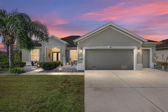 ranch-style house with a garage and a lawn