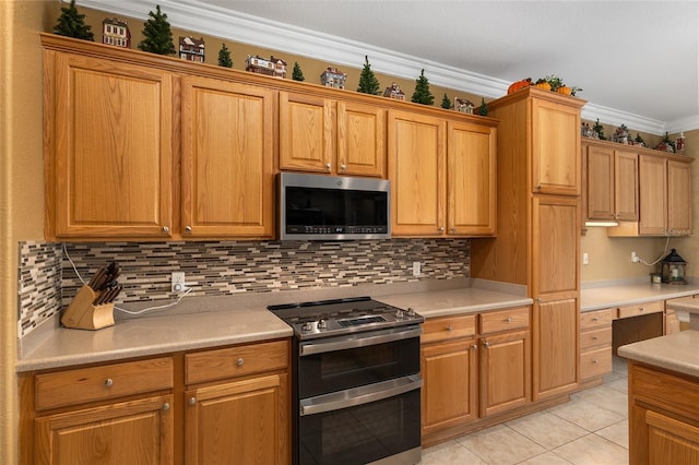 kitchen with appliances with stainless steel finishes, crown molding, tasteful backsplash, and light tile patterned floors