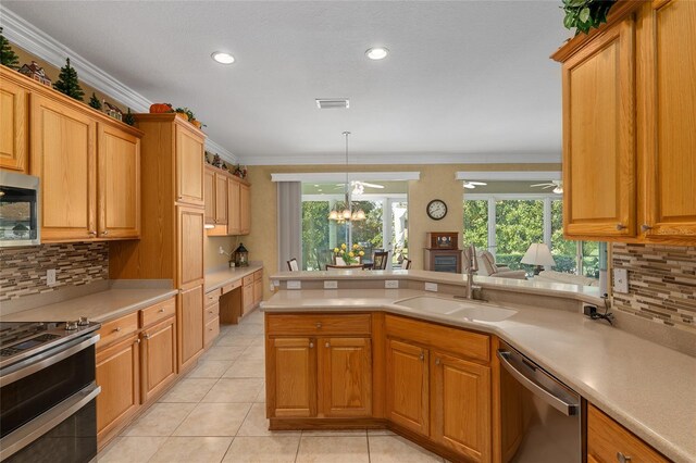 kitchen with hanging light fixtures, stainless steel appliances, sink, crown molding, and light tile patterned flooring